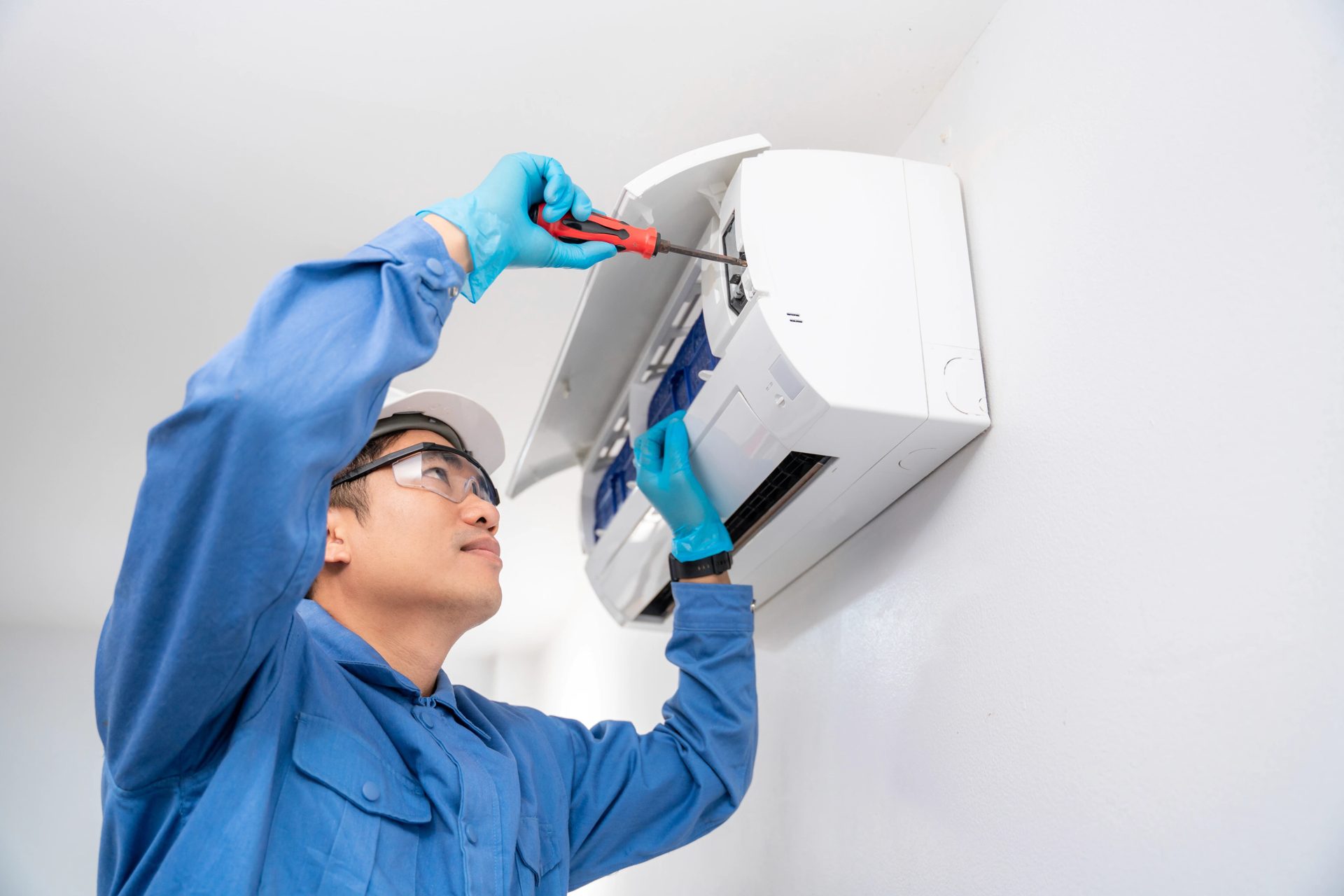 HVAC technician servicing a wall-mounted air conditioning unit