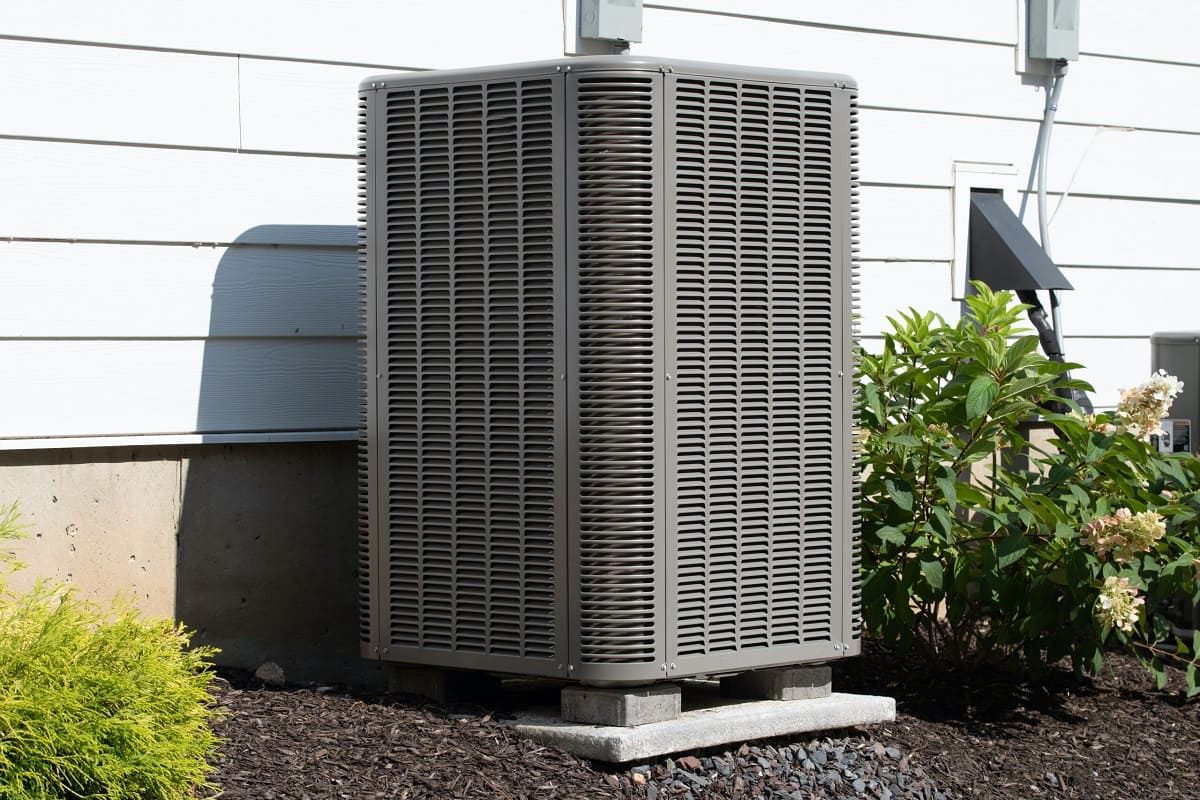 Outdoor air conditioning condenser unit beside a home